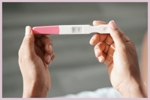 Manos sosteniendo test de embarazo positivo