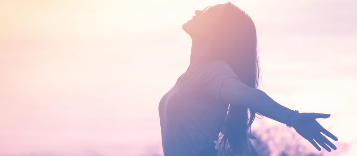 Mujer al atardecer con los brazos abiertos