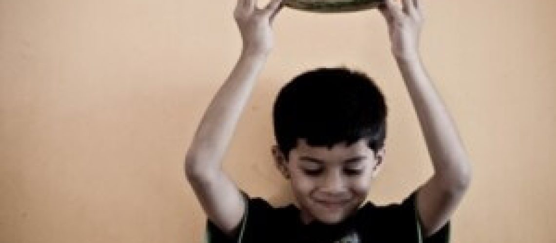 Niño sosteniendo una sandía sobre su cabeza